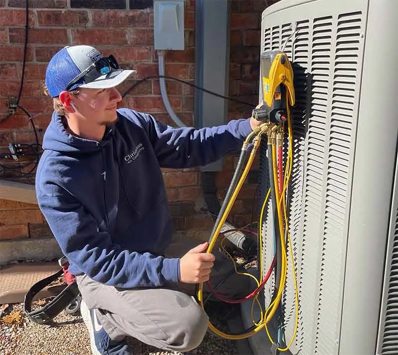 Carlsbad HVAC technician servicing outdoor AC condenser with digital manifold gauges