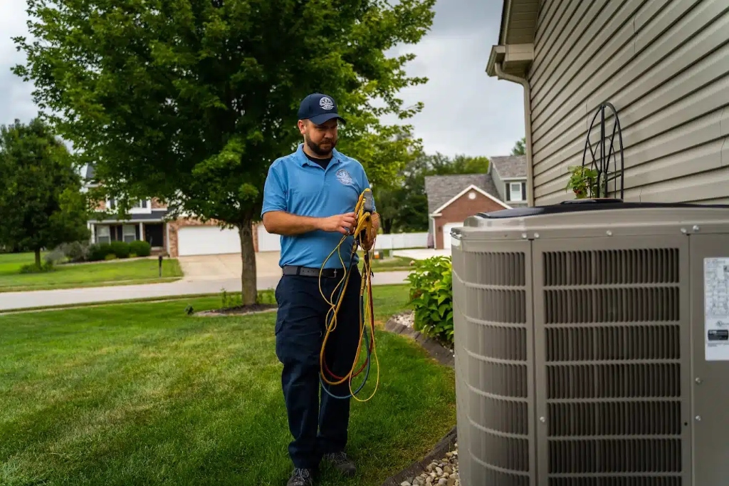 HVAC technician inspecting outdoor heating and heat pump condenser with manifold gauges