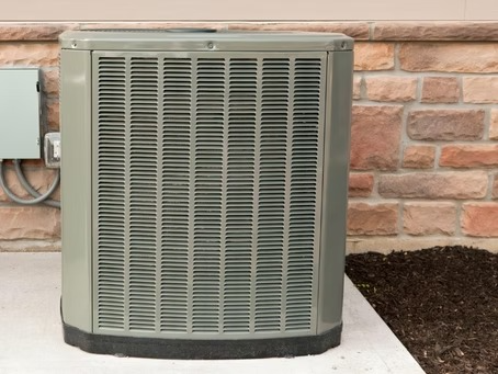 Outdoor AC condenser installed on elevated pad next to home exterior in Carlsbad