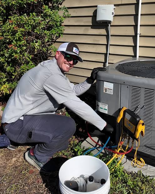 Technician testing outdoor heat pump pressures with digital diagnostic manifold gauges and vacuum lines