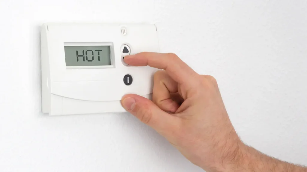 Adjusting digital thermostat during hot Rancho Bernardo summer afternoon