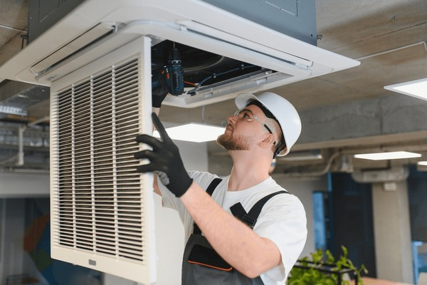 Technician installing ductless ceiling unit in Oceanside home